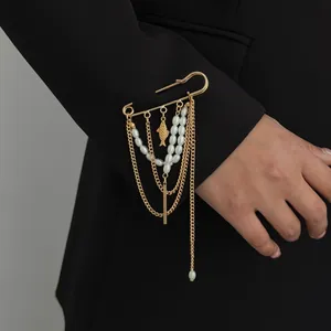 Detailopname van een gouden kwastjesbroche met parels en een visbedel op een zwarte mouw