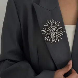 Gros plan d'une broche soleil en argent épinglée sur le revers d'un blazer gris foncé