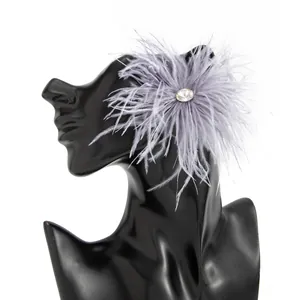 Détail d'une élégante boucle d'oreille en plumes grises avec un strass clair au centre.