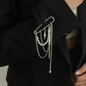 Detail van stijlvolle veiligheidsspeld broche met parels en kettingkwastjes