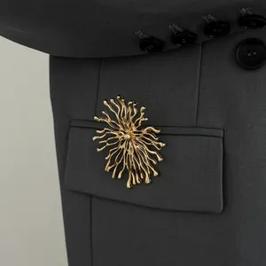 Gros plan d'une broche soleil dorée artistique épinglée sur une poche de costume gris