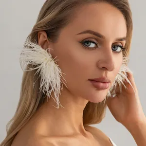 Gros plan de boucles d'oreilles élégantes en plumes d'autruche blanches et strass.