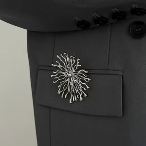 Gros plan détaillé d'une broche créative en relief corail argenté sur une veste de costume grise