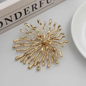 Gros plan d'une broche créative dorée en forme de soleil au design corail