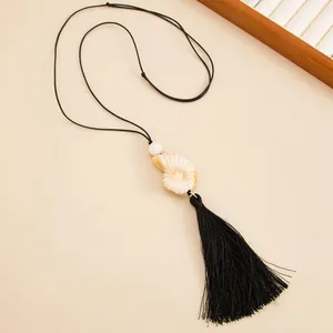 Close-up detail of holiday style adjustable shell necklace with elegant black tassel pendant