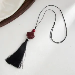 Detailed view of the resin scallop pendant and long black tassel on a luxury background