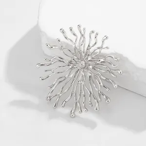 Gros plan d'une broche rayon de soleil argentée avec une texture inspirée du corail.