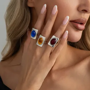 Vintage silver French rings with square colored stones on model's hand detail view