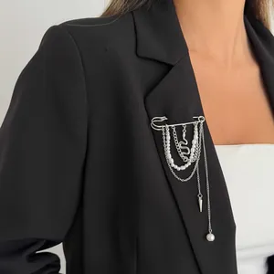 Gedetailleerde weergave van een zilverkleurige veiligheidsspeld-broche met parels en kettingen