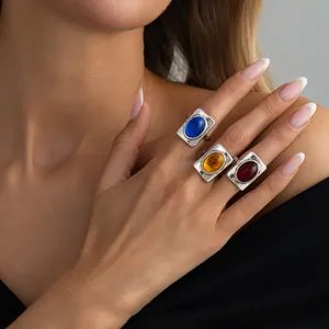 Close-up of three French vintage square rings with blue amber and red gemstones on hand