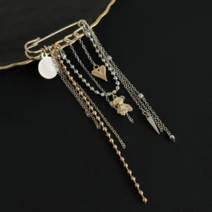 Macro view of gold heart and teddy bear charms on a layered tassel chain brooch