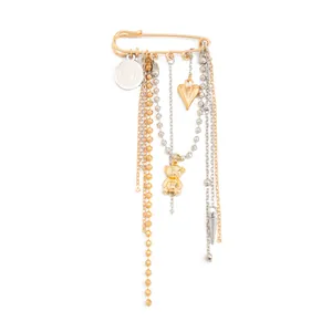 Detailed view of gold and silver tassel brooch with heart and teddy bear charms