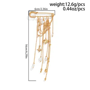 Detail view of a gold safety pin brooch featuring heart charms and long tassels