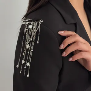 Close-up detail of a silver safety pin brooch with heart charms and long tassels