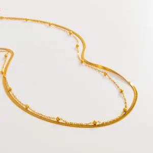 Détail d'une chaîne de corps en acier doré avec maille serpent plate et perles