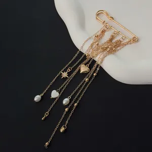 Detailed view of the elegant gold safety pin brooch with heart charms and star tassels