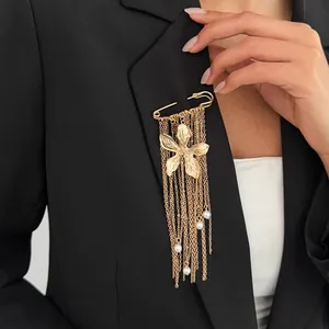 Close-up of a gold flower brooch with long tassel chains and pearl accents on a suit