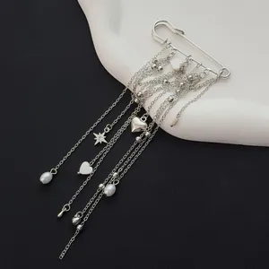 Detail view of a silver safety pin brooch with elegant heart and pearl tassels.