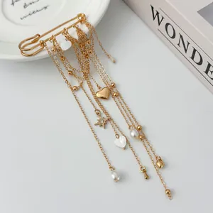Close-up detail of a gold tassel safety pin brooch with heart charms and elegant pearls