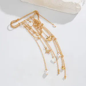 Close-up of a gold-colored safety pin brooch with elegant heart and star tassel chains