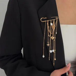Elegant gold safety pin brooch with heart charms and pearl tassels on a black blazer.
