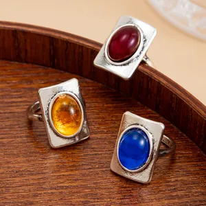 Detailed view of vintage square rings with colorful gemstones on a wooden tray