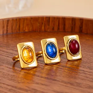 Close-up view of three vintage rectangular gemstone rings in gold finish on a wooden tray