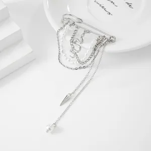 Gedetailleerd overzicht van een zilveren kwastjesbroche met gelaagde kettingen en parels.