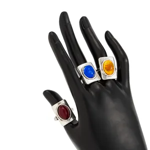 Detail shot of vintage square rings with colorful gems on a black mannequin hand.