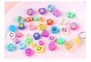 Detailed view of colorful fruit and smiley face polymer clay beads for DIY jewelry making.