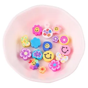 Colorful fruit and smiley face polymer clay beads in a pink bowl for DIY jewelry