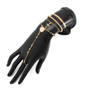 Detalle de cadena de mano dorada con colgante de cruz y cadena de serpiente en modelo