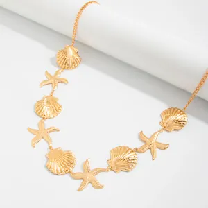 Detail van boheemse gouden bodychain met zeester en schelp bedels op een witte achtergrond