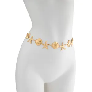 Detailopname van boheemse gouden zeester en schelp metalen heupketting op pop