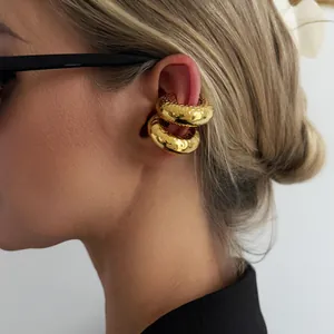 Close-up of chunky gold stainless steel ear cuffs with lava texture on a model's ear.