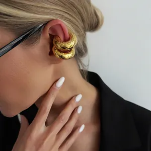 Close-up detail showing two gold C-shaped lava texture ear cuffs on a model's ear