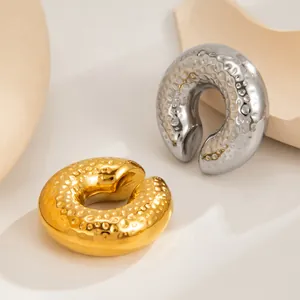 Close-up of gold and silver stainless steel C-shaped ear cuffs with molten lava texture.