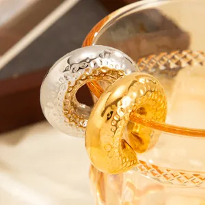Close-up of gold and silver hammered lava texture C-shaped stainless steel hoop earrings
