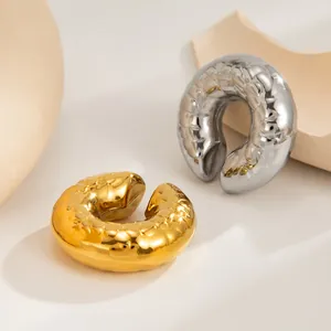 Detail of chunky textured stainless steel C-shaped ear cuffs in gold and silver finish