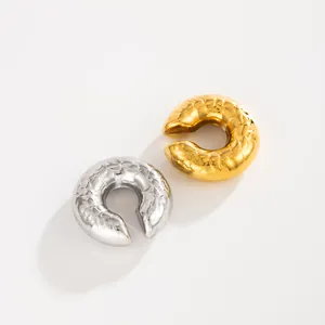 Detailed shot of textured gold and silver stainless steel C-shaped lava ear cuffs