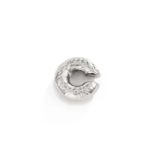 Macro shot of a silver stainless steel C-shaped ear cuff with molten metal texture.