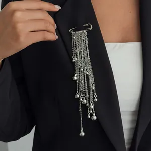 Close-up detail of a silver multi-tassel chain safety pin brooch on a black blazer