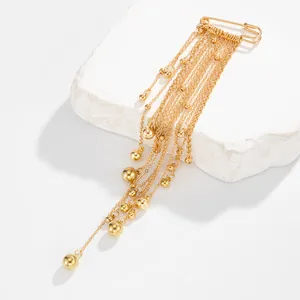 Detailed view of gold multi-tassel chain brooch with metallic beads on a white stone