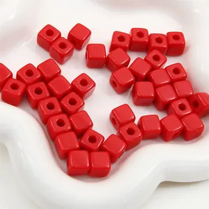 Dichtbij van rode acryl kubuskralen met middengat voor DIY sieraden maken.