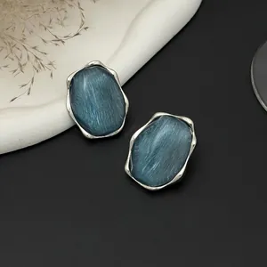 Primo piano di anello geometrico color argento con intarsio blu a trama ondulata