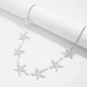 Detail van zilveren zeester lichaamsketting met witte parels voor de strandstijl