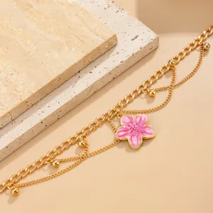 Detail of gold chain anklet featuring a pink enamel flower pendant for summer beach style.