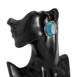 Dettaglio di un anello geometrico color argento con una gemma ovale blu testurizzata