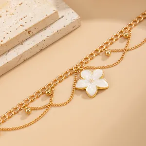 Detailed close-up view of a gold multi-layer anklet with a white enamel flower charm.