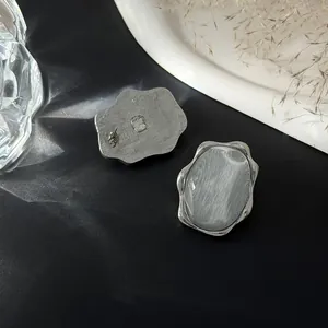 Vista dettagliata di orecchini color argento con motivo a onde d'acqua e design geometrico